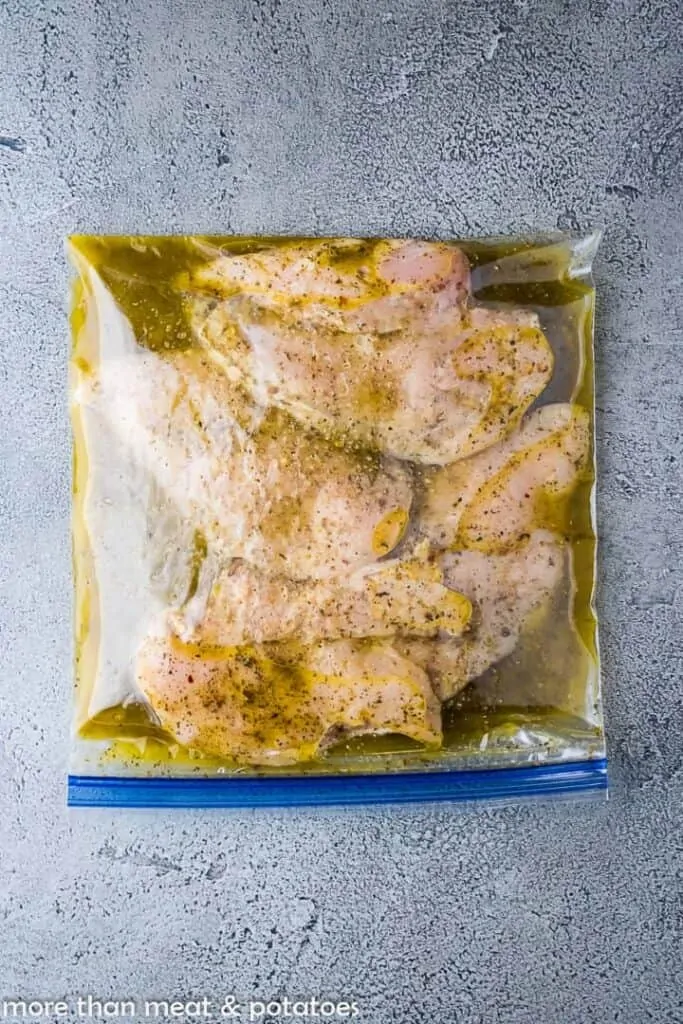 The raw chicken marinading in a zip top freezer bag.