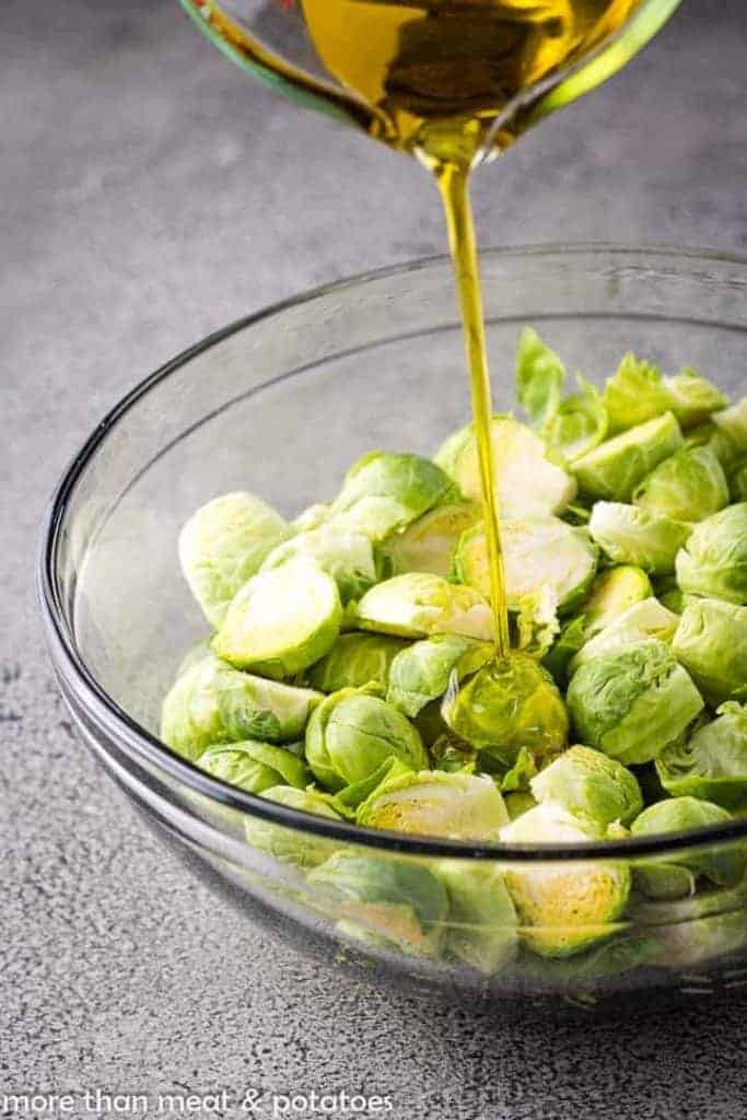 Brussels sprouts being drizzled with olive oil.