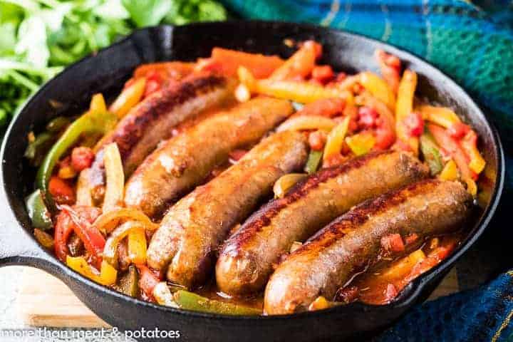 Italian sausage and cooked peppers in an iron skillet.