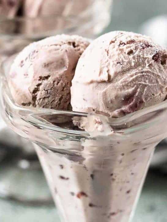 Scoops of cherry ice cream in a glass ice cream holder.