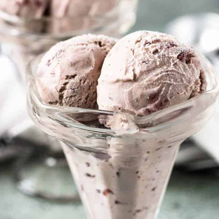Scoops of cherry ice cream in a glass ice cream holder.