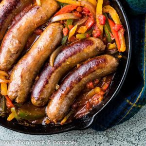 Top down image of italian sausages and bell peppers in a cast iron pan.