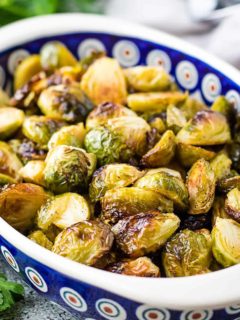 Blue oval dish filled with roasted brussel sprouts.