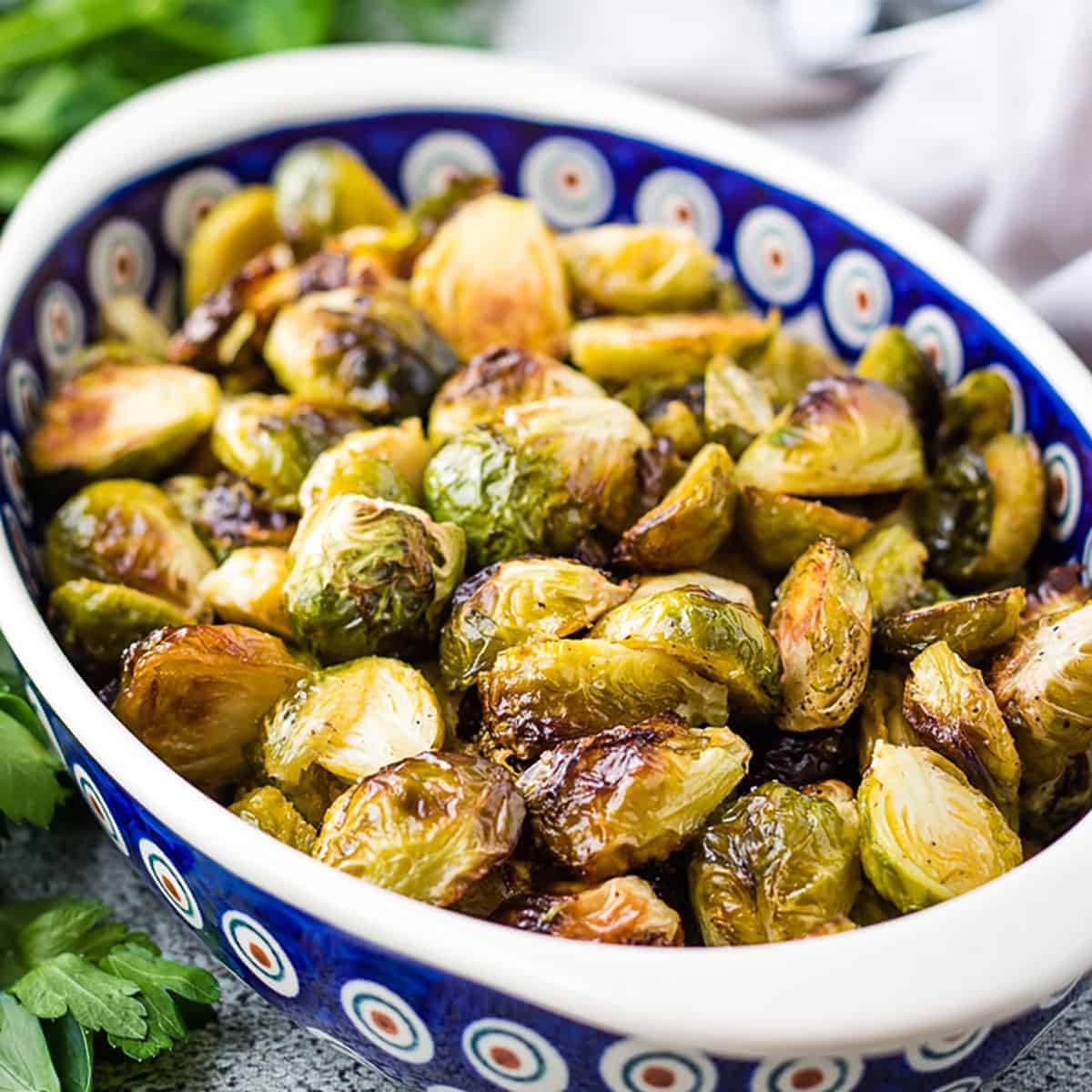 Blue oval dish filled with roasted brussel sprouts.