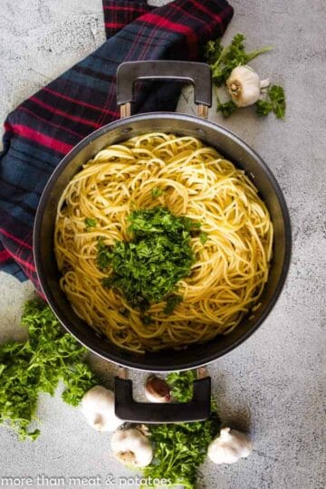 Cooked spaghetti tossed with oil mixture and topped with parsley.