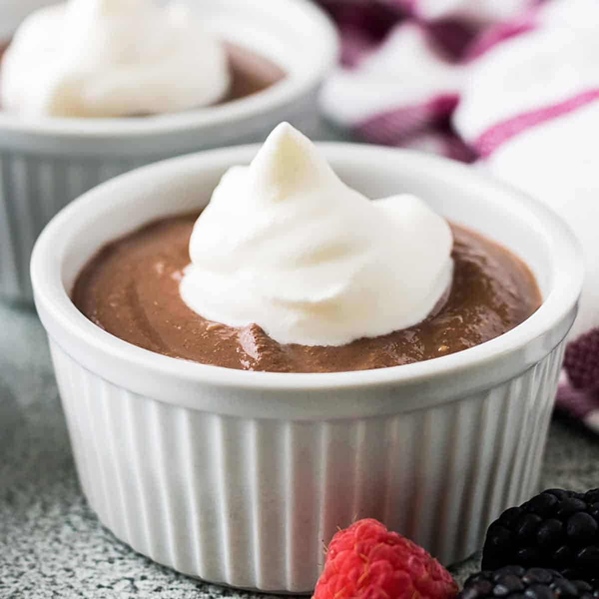 Ramekin filled with homemade chocolate pudding and topped with homemade whipped cream.