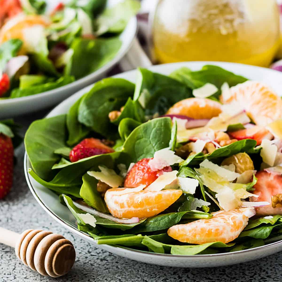 Bowl of spinach salad with strawberries and orange slices.