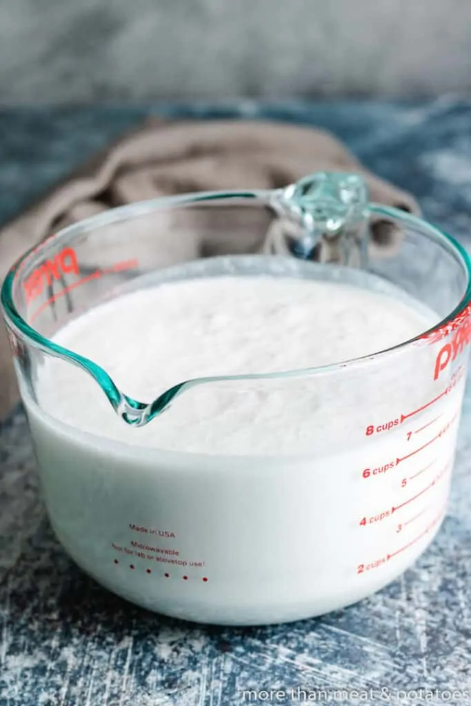 Coconut milk and cream of coconut in a glass measuring cup.
