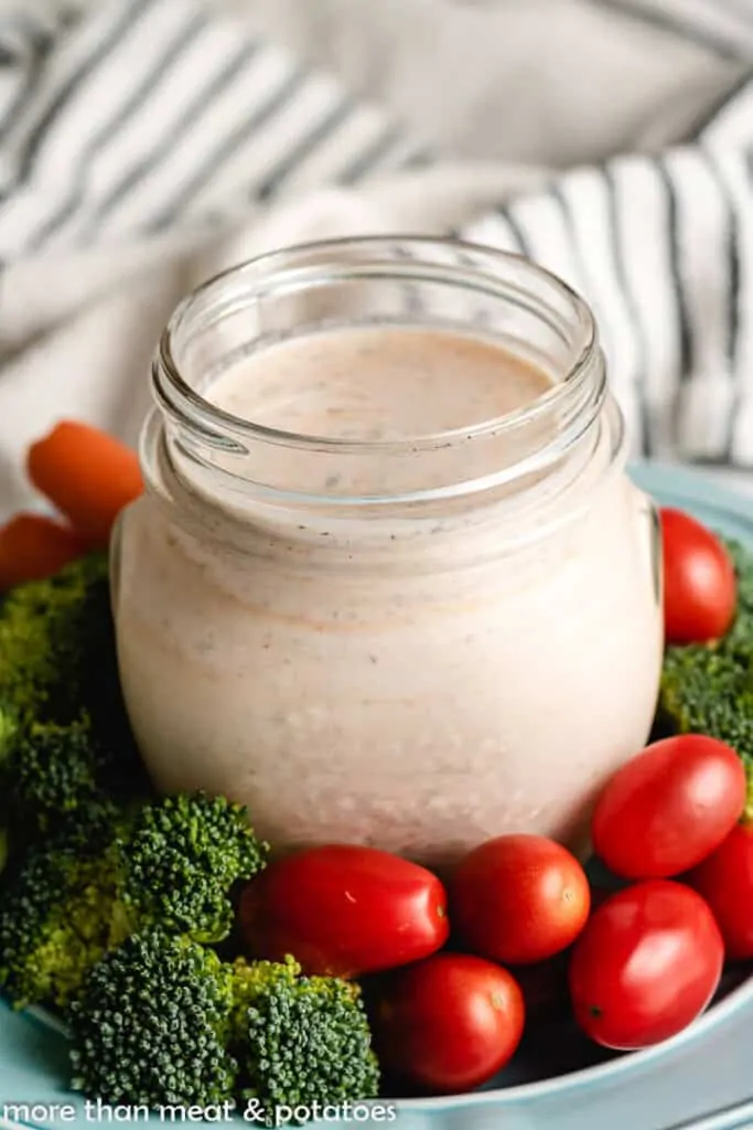 The finished dressing in jar served with fresh broccoli and tomatoes.