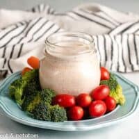 The no mayo ranch dressing in a small jar surrounded by fresh veggies.