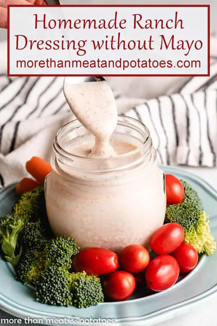 A spoon being dipped into the ranch dressing in a jar.