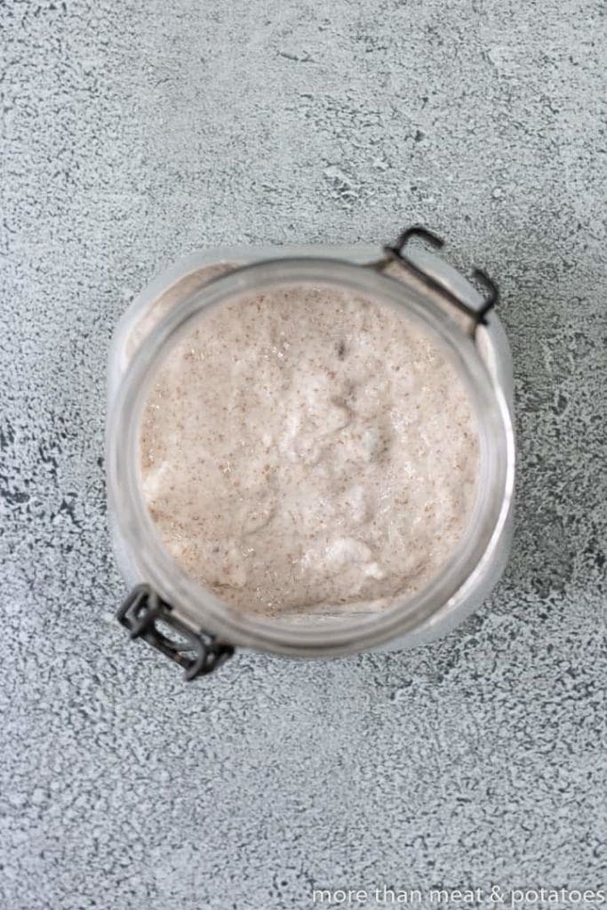 Top down view of flour, starter, and water in a jar.