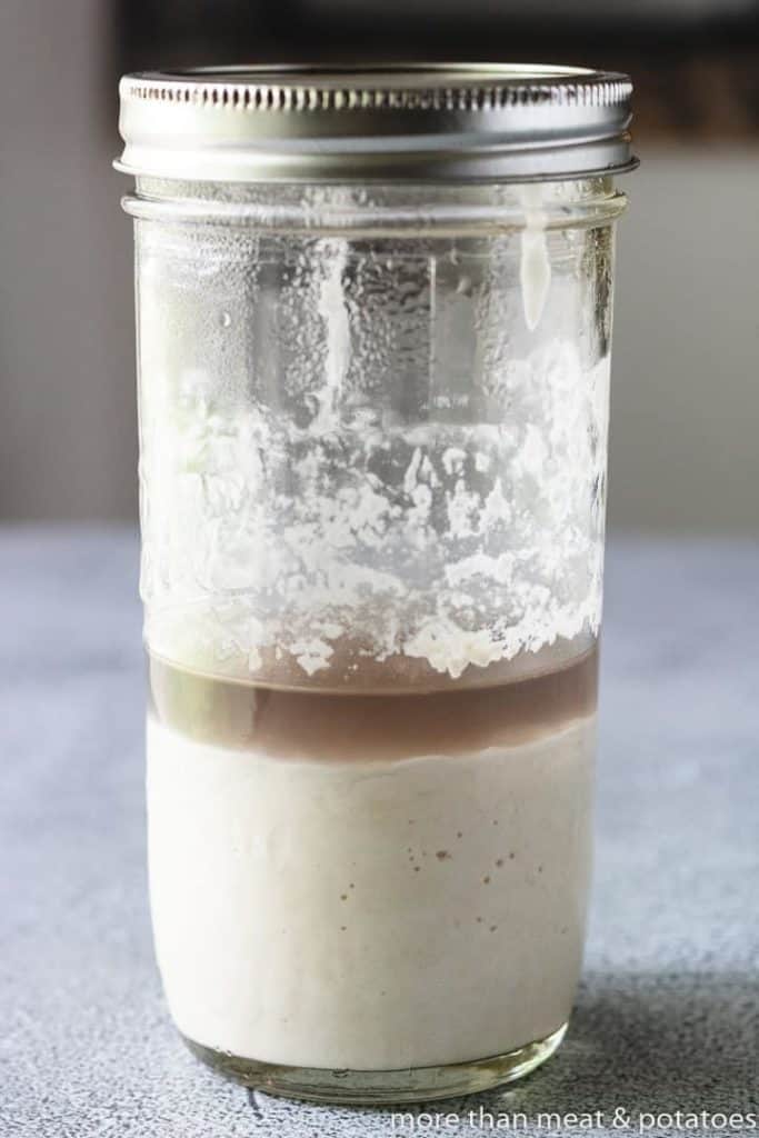 Jar of sourdough starter with a layer of hooch on top.