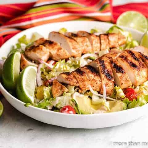 Mexican grilled chicken salad served with lime wedges.