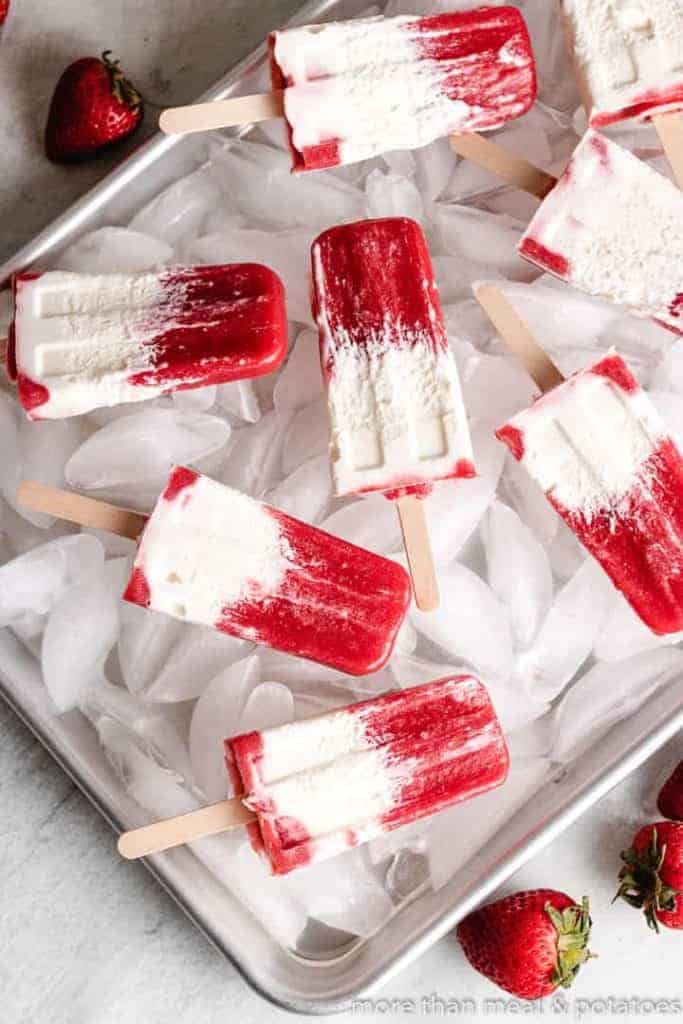 Top down view of the berries and cream popsicles on a pan.