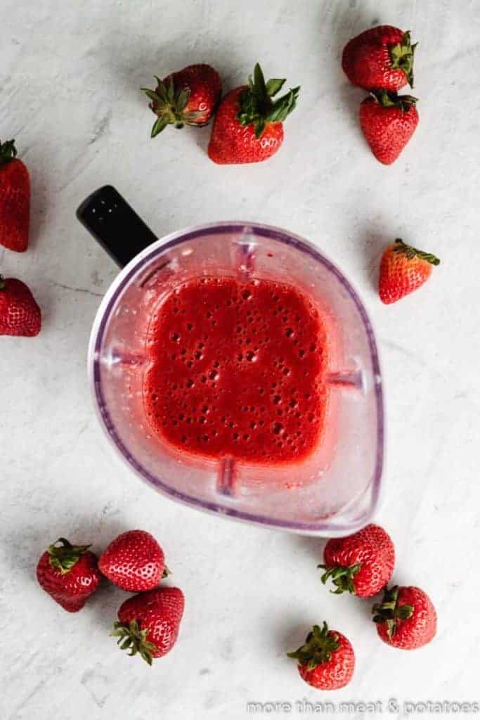 Berries, honey, and other ingredients pureed in a blender.