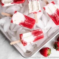 Five strawberry and cream popsicles on an iced pan.