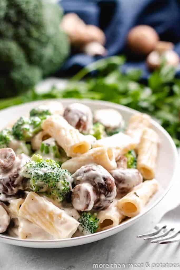 Bowl of mushroom broccoli pasta next to a fork.
