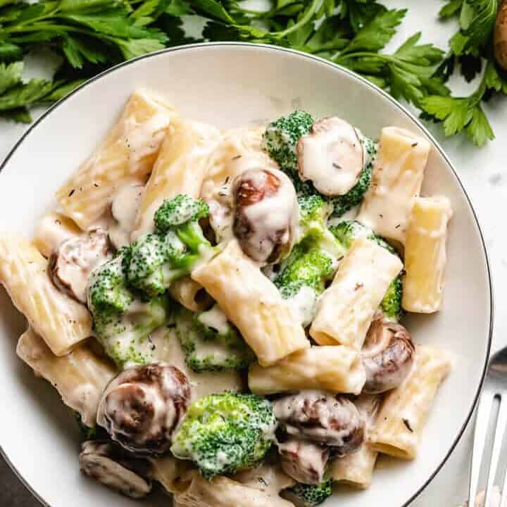 Mushrooms, broccoli, and pasta on a white plate.