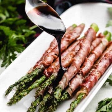 The glaze being drizzled over the asparagus.