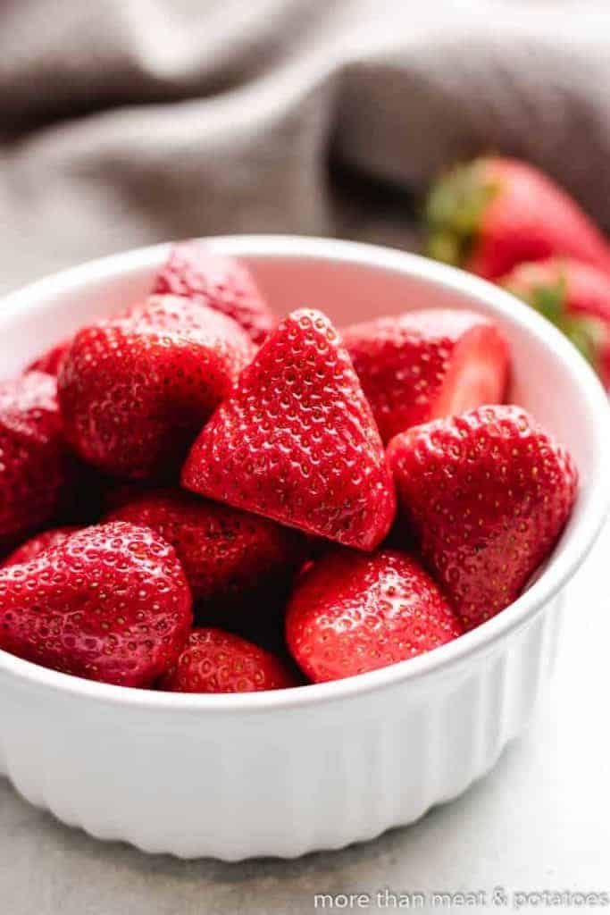 Fresh strawberries in a white ramekin.