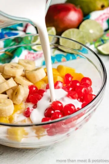 The coconut milk dressing being poured over the fruit.