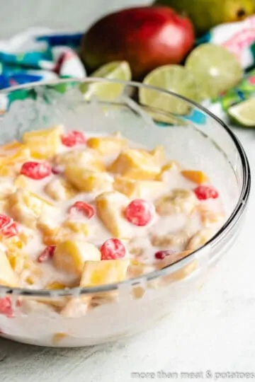 The fruit salad and dressing have been combined in the mixing bowl.