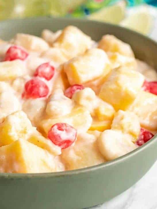 The tropical fruit salad with coconut served in a green bowl.