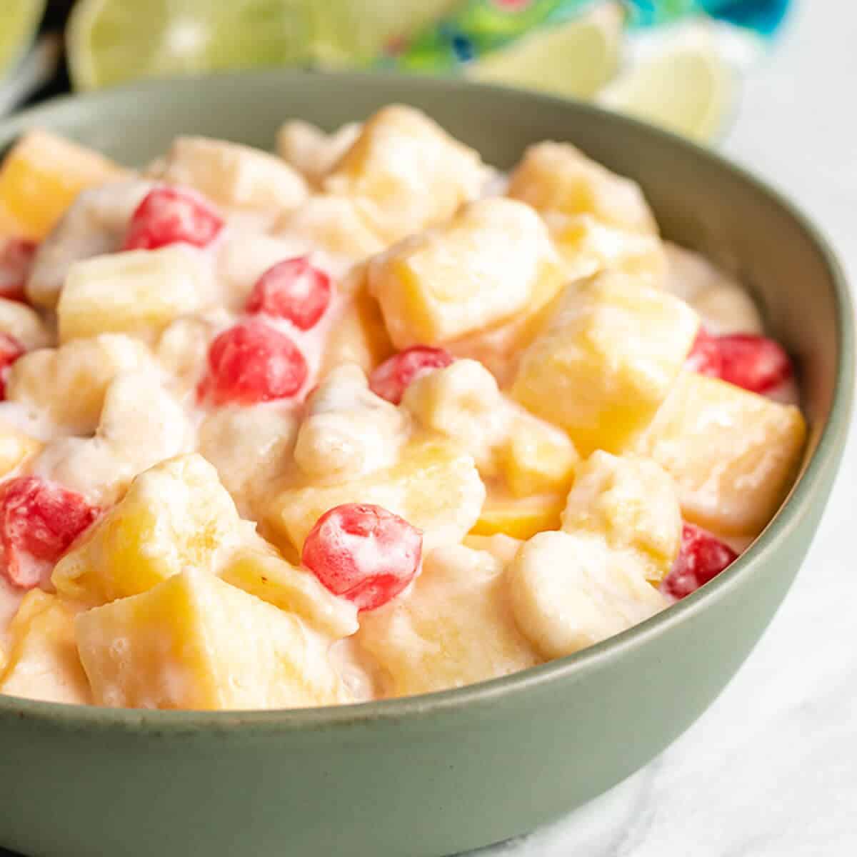 The tropical fruit salad with coconut served in a green bowl.
