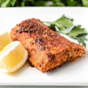 A blackened mahi mahi filet on a square plate.