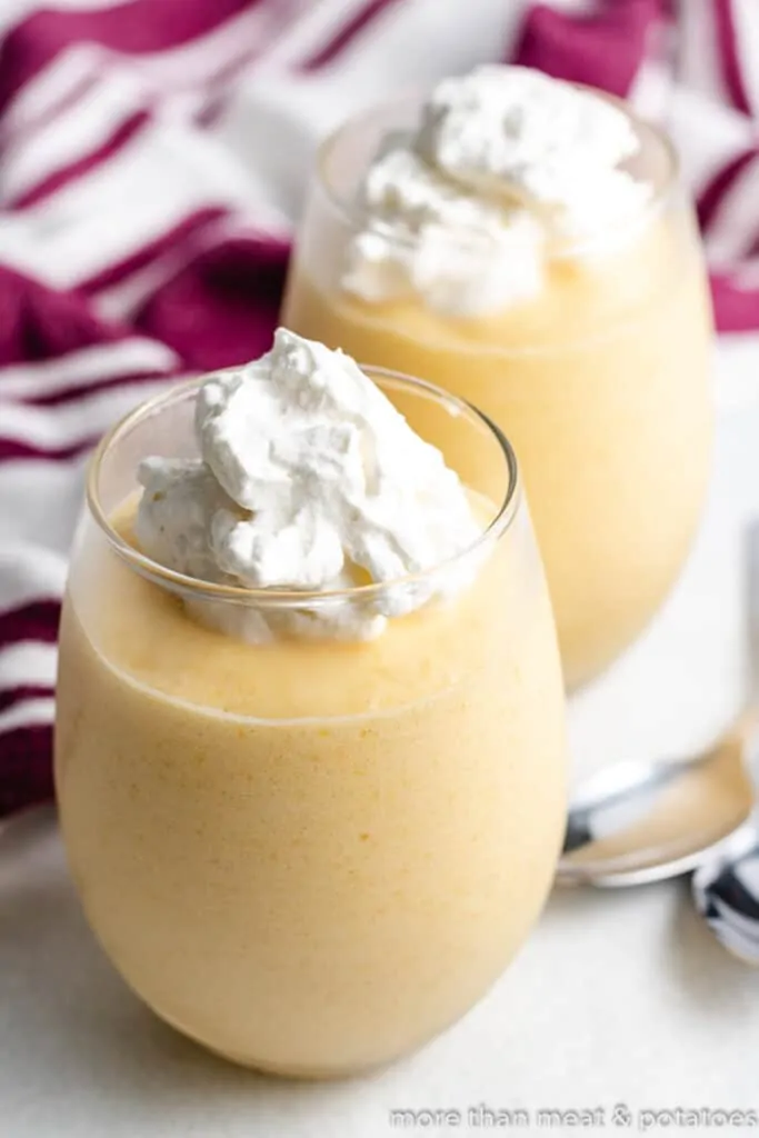 The dessert served in glasses with whipped cream.