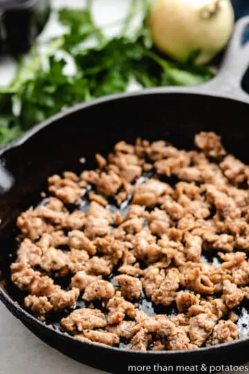 Sausage cooking in a cast iron skillet.