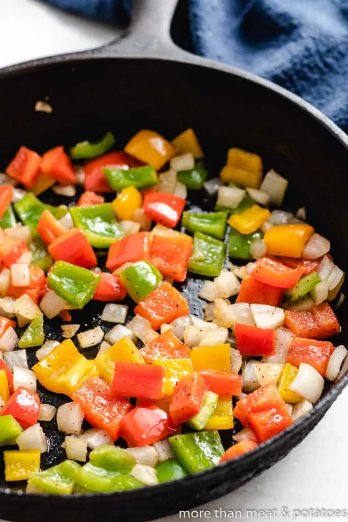 Diced peppers and onions cooking in the skillet.