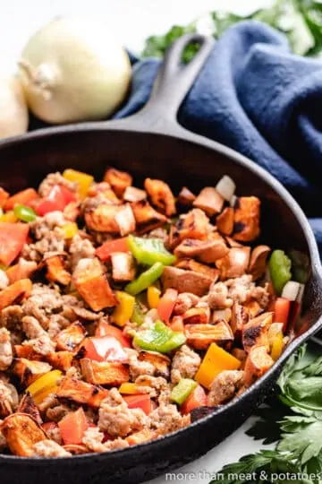 The meat and potatoes added to the peppers and onions.