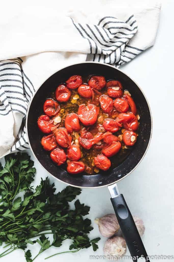 Tomatoes, garlic, and other ingredients in the pan.