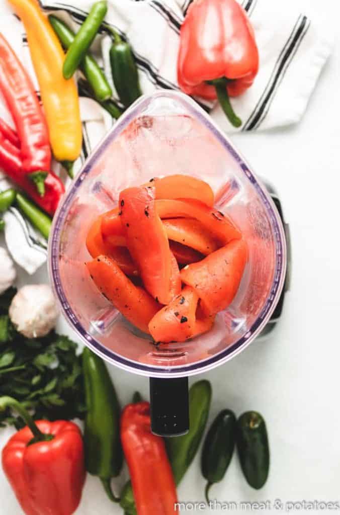 An aerial view of peeled peppers in a blender.