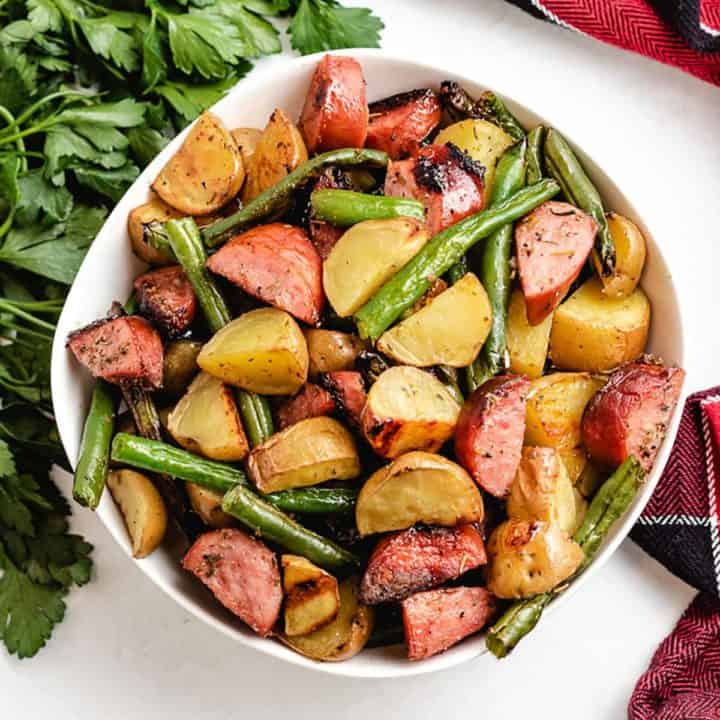 The cooked sausage green beans and potatoes in a bowl.