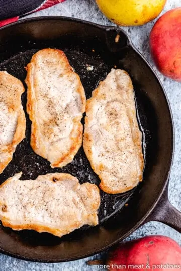 The pork cutlets cooking in a skillet.