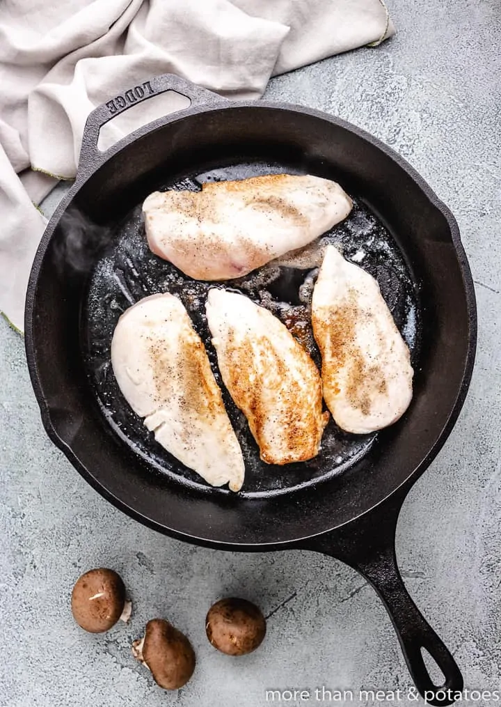 The chicken breasts cooking in a skillet.