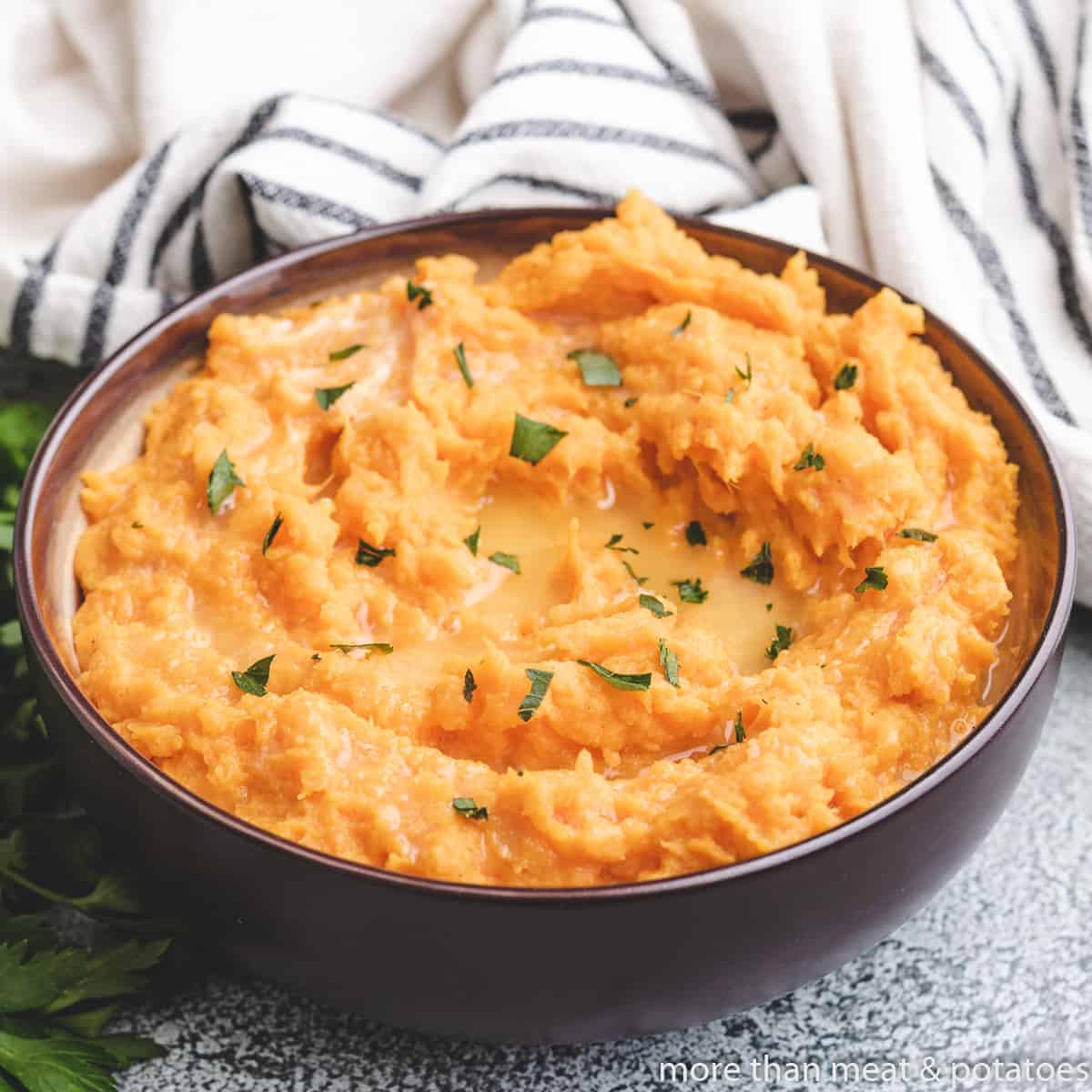 Mashed sweet potatoes in a bowl garnished with parsley.