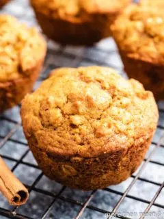 Four pumpkin oatmeal muffins on a cooling rack.
