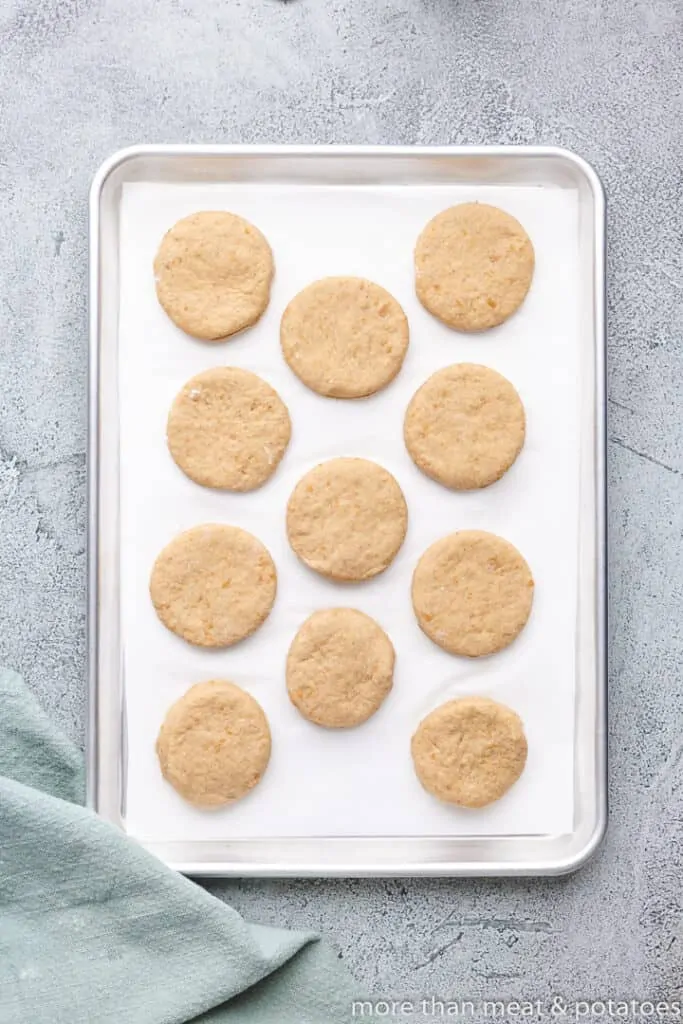 The raw biscuits sitting on a lined sheet pan.