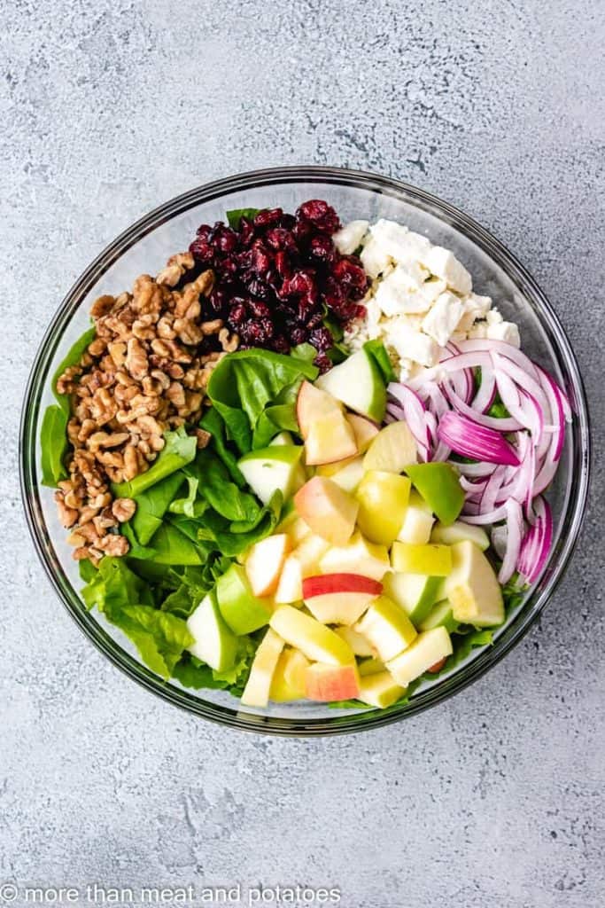 Lettuce, onion, and other ingredients in a mixing bowl.