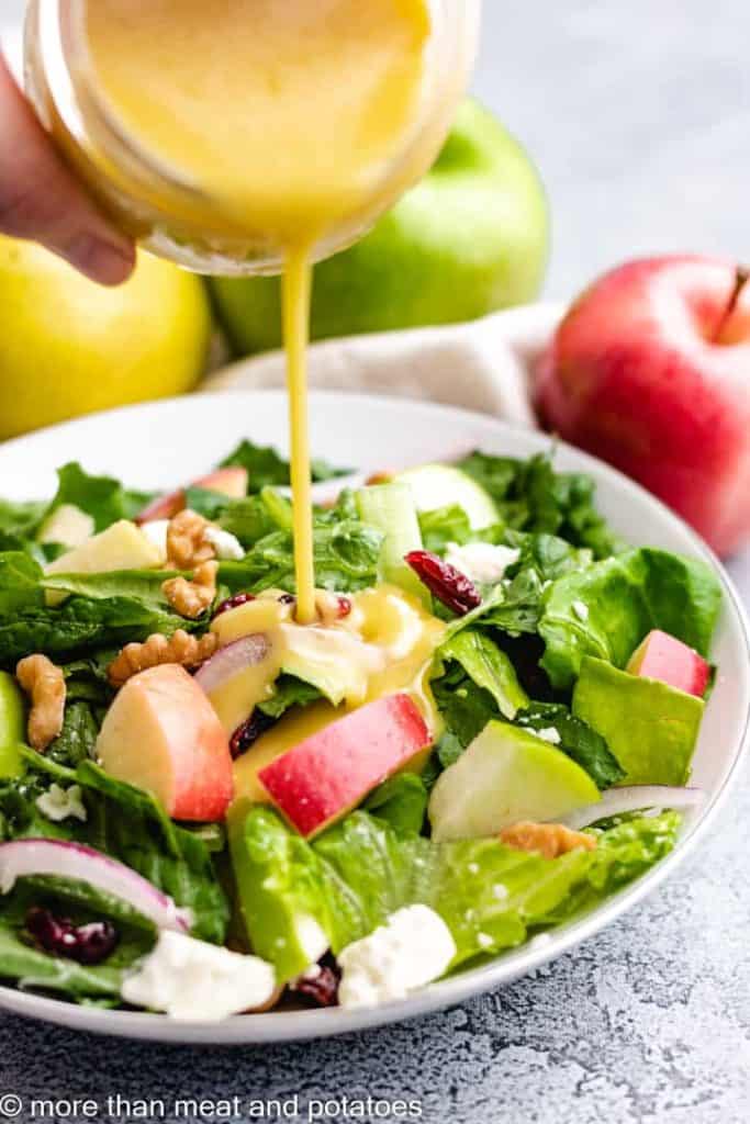 The salad being dressed with an apple cider vinaigrette.