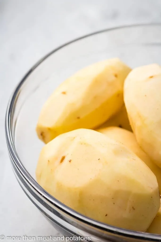 Peeled potatoes in a mixing bowl.