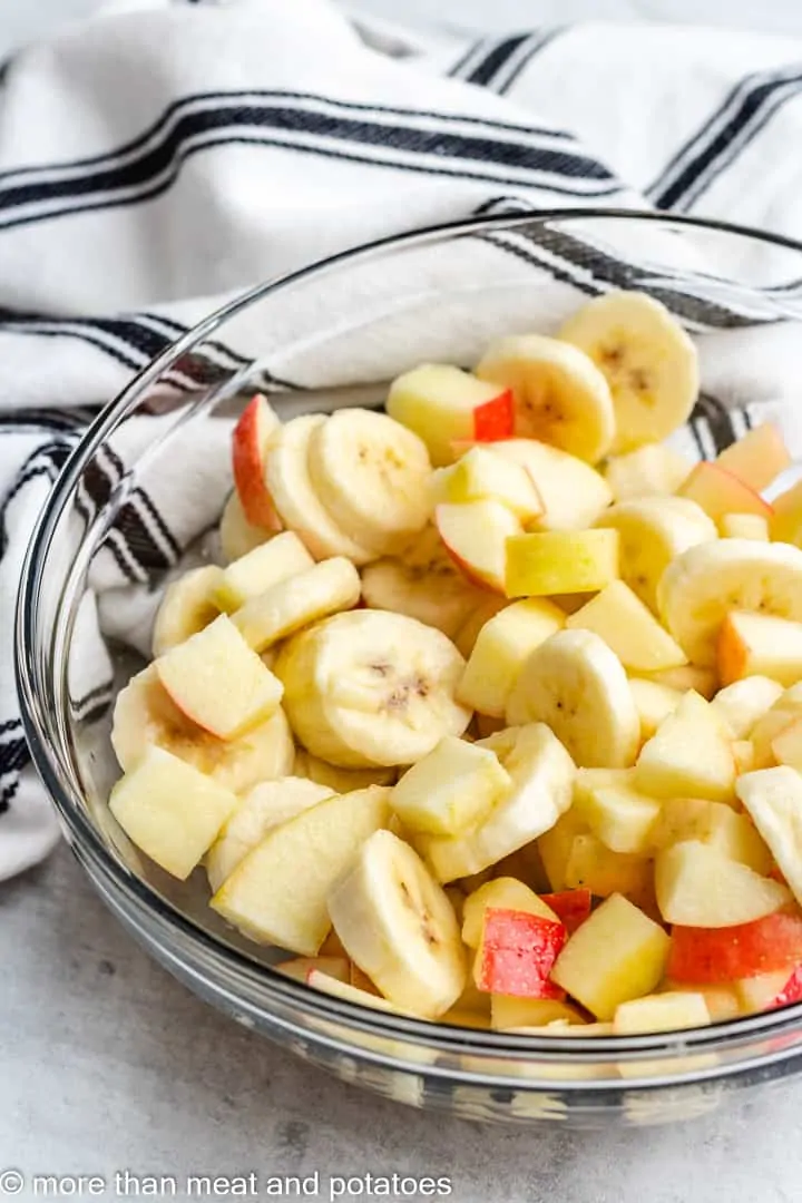 Easy Cranberry Fruit Salad Sliced bananas and apples in a mixing bowl.