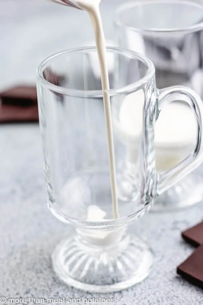 Heavy cream being poured into a glass mug.
