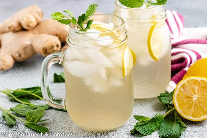 Two glass mugs of ginger infused water garnished with mint.
