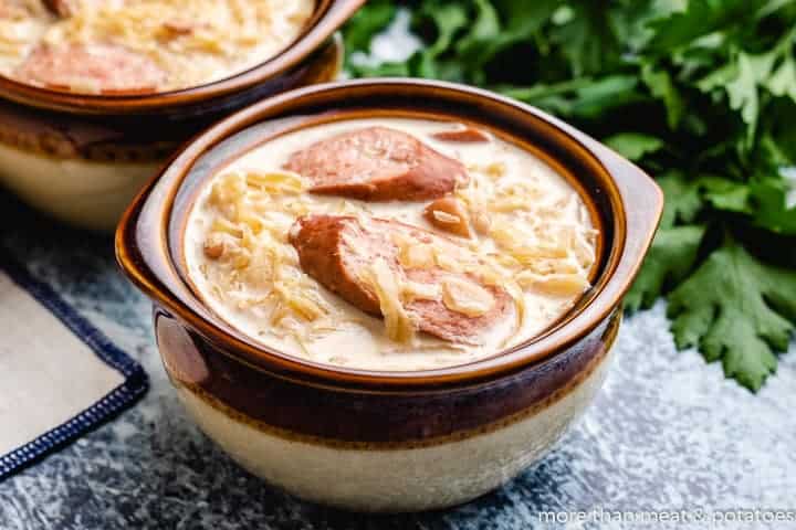 Sausage and sauerkraut soup served in earthenware bowls.