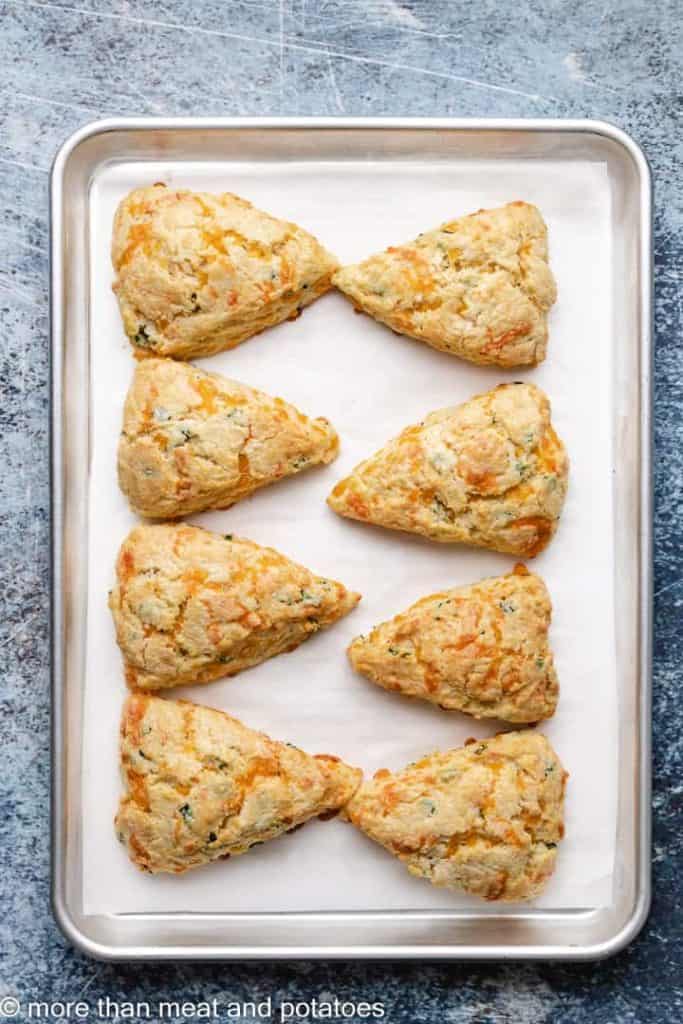Eight fresh baked scones on a sheet pan.